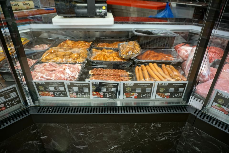 Theke mit marinierten Hähnchenteilen, Adana-Spießen und Rinderwurst, mit Preisschildern